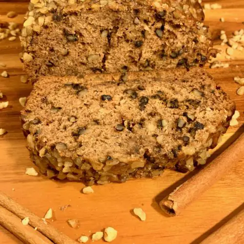 cinnamon walnut banana bread on cutting board surrounded with walnuts and cinnamon sticks