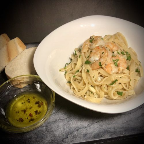 shrimp scampi on marble top with parisian bread and bread oil dip