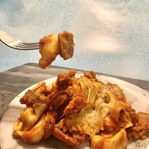 cheesy tortellini with sausage on fork