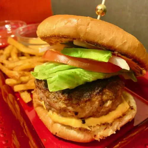 california turkey and sausage burger with sriracha mayo, lettuce, tomato, onion, jalapeno and avocado. It is served alongside cajun fries and two dipping sauces