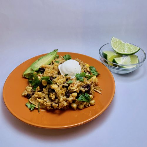 slow cook mexican shredded chicken and corn plated with sour cream and avocado
