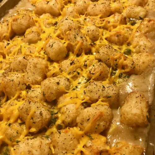 Shepherd's pie tater tot casserole in baking pan with melted cheddar cheese and dried parsley over the top